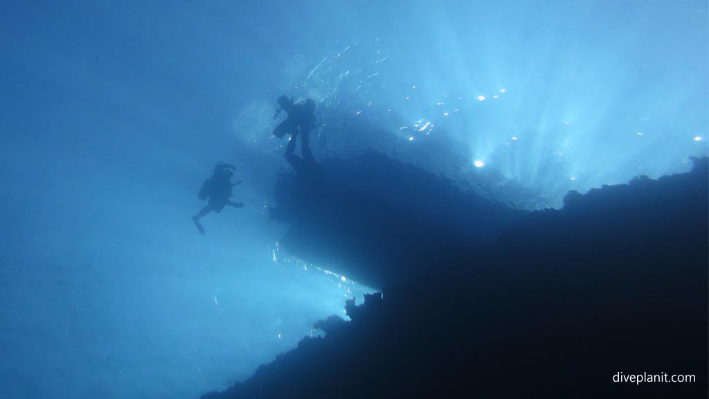 Divers silhouetted against the boat at Subway diving Vomo at Subway in the Fiji Islands by Diveplanit