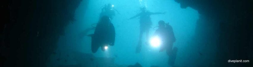 Silhouetted divers in cave entrance at south west rocks banner