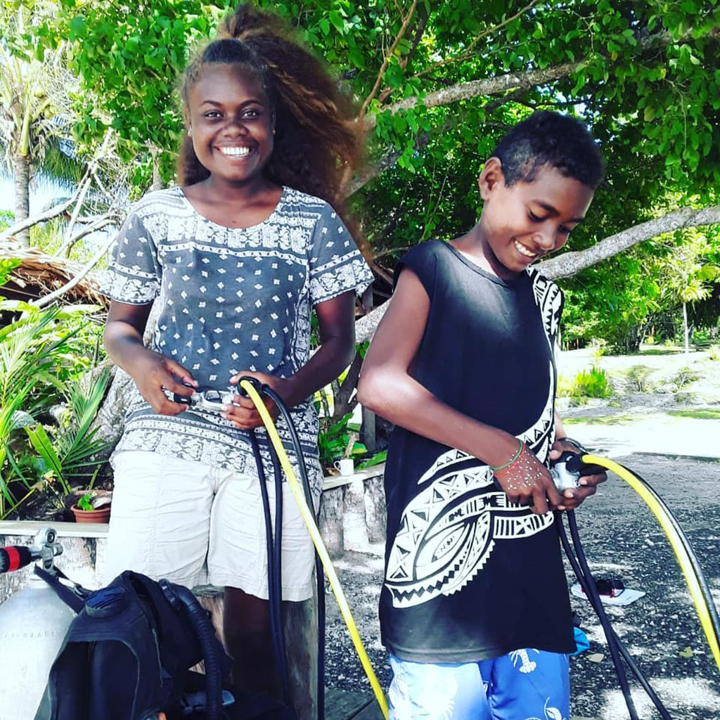 2 Dive Munda Youth Sponsorship | Teaching Solomons Youth how to dive - caroline and grady with tanks While the Solomon Islands’ borders have been closed, Dive Munda has been teaching local youth how to dive with a target to train 80 by the end of the year.